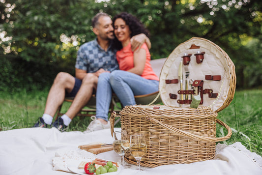 Couple sitting together outdoors next to a heart-shaped willow picnic basket — the perfect wedding gift