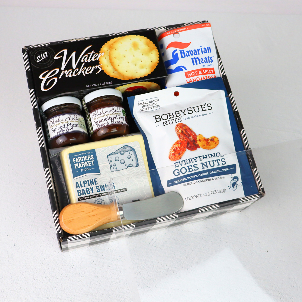 Assorted food items including crackers, meats, and nuts in a box on a white background