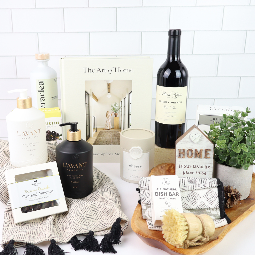Collection of home products including a bottle of wine, candles, and soaps on a white surface with a 'The Art of Home' magazine.