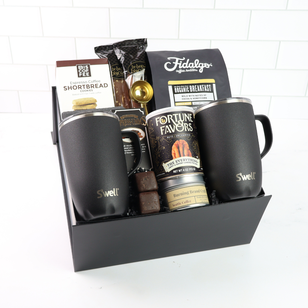 Gift basket with coffee mugs, snacks, and coffee packages on a white background