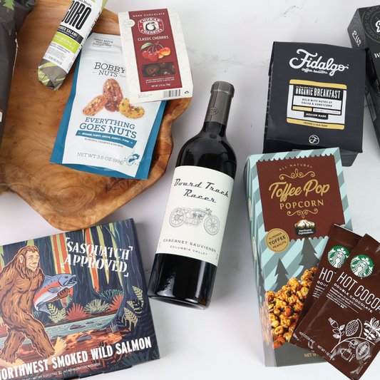 Assorted food products including a bottle of wine, snacks, and packaged goods on a white surface.